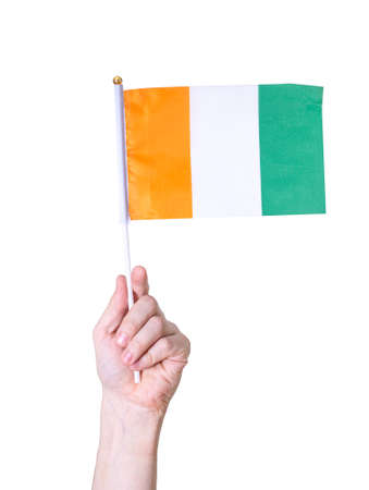 A hand holds a flag The flag of the Ivory Coast country on a white isolated background. The concept of the country.の写真素材