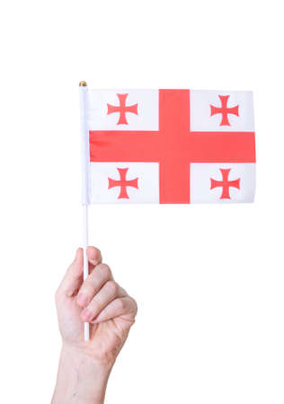 A hand holds the flag of Georgia against a white insulated background. Concept of the country.の写真素材