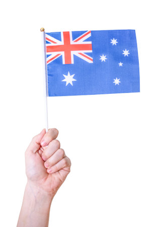 A hand holds the flag of Australia against a white isolated background. The concept of a great country.の写真素材