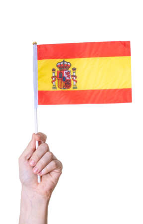 A hand holds the flag of Spain on a white isolated background. The concept of a great country.の写真素材