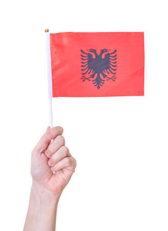 A hand holds the flag of Albania against an isolated white background. The concept of a great country.の写真素材