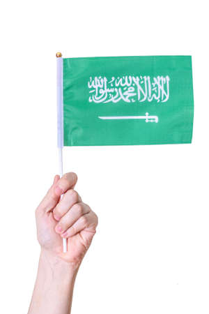 A hand holds the flag of the country of Saudi Arabia. on a white isolated background. The concept of a great country.の写真素材