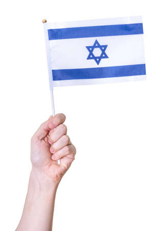 A hand holds the flag of Israel on a white isolated background. The concept of a great country.の写真素材