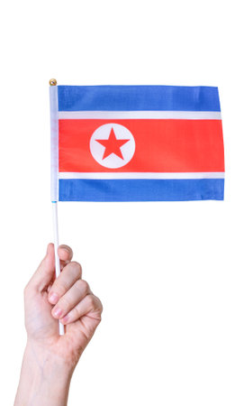 The hand holds the Flag of the country of the DPRK on a white isolated background. The concept of a great country.の写真素材