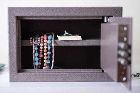 Money and jewelry in an open safe on the table. There is money and beads in the open safe.の写真素材
