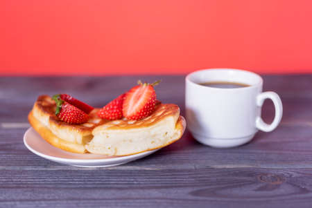 Belgian waffles with strawberries and coffee on a wooden, dark table. The concept of a delicious breakfast.の写真素材