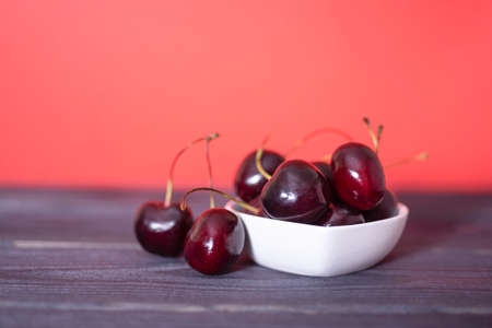 Cherry in a ceramic saucer on a black and red background. The concept of tasty and healthy food.の写真素材