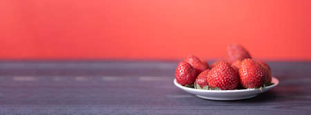 Fresh strawberries in a white plate on a dark wooden background. The concept of fresh and healthy food. copyspace.の写真素材