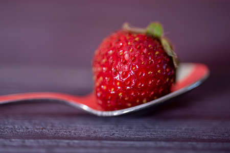 Red strawberries on a silver spoon, on a dark, wooden black background. The concept of delicious and healthy food.の写真素材