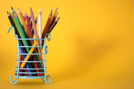 Lots of colorful drawing pencils in a green glass on a yellow background, space for copying. The concept of Knowledge Day or International Literacy Day.の写真素材