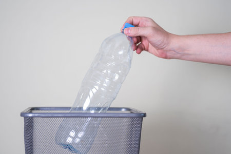 Throw a plastic bottle in the trash on a gray background. The concept of ecology and cleanup.
