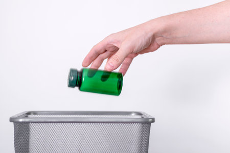 Hand tosses a plastic small bottle in the trash. The concept of separate waste collection and recyclingの写真素材