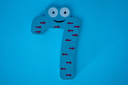 Cute and colorful wooden number 7 with eyes on a blue background. The concept of going back to school. close-up shot.の写真素材