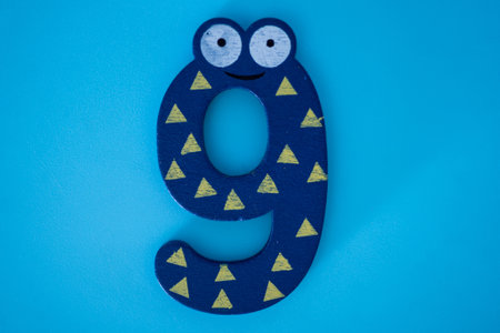 Cute and colorful wooden number 9 in blue with eyes on a blue background. The concept of going back to school. close-up shot.の写真素材