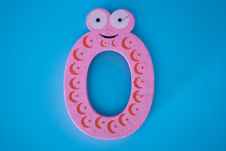 Cute and colorful wooden numeral 0 with eyes on a blue background. The concept of going back to school. close-up shot.の写真素材