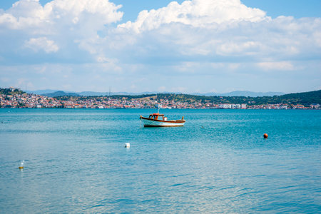 An old and small fishing boat in the background of a Turkish town on a summer and sunny day. The concept of tourism and travel.の写真素材