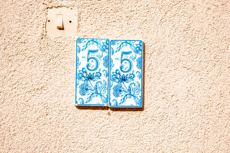 Number plate 55, blue color plate on beige wall. house numbering.