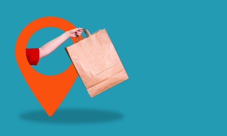 A creative banner featuring a lady's hand with a paper bag, courier delivery service in red marker with a pin, blue background with copy spacing.の写真素材