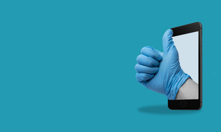 Art collage, Hand showing thumbs up gesture from cell phone, on blue background with space for ads. Modern art. modern design.の写真素材