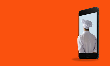 The concept of cooking and cooking apps. A chef in a phone on a red background with space for text. Mobile apps for chefsの写真素材