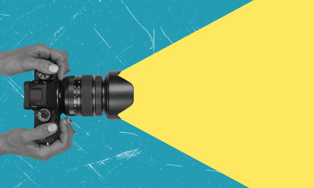 Contemporary art collage. Human hand holding a camera with space for text. Concept of advertising and promotion.の写真素材