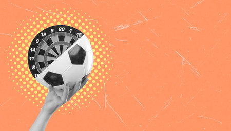 A hand holds a soccer ball, pairing it with a dart board on a bright orange background. This juxtaposition symbolizes the combination of sport and precision, emphasizing creativity and fun.の写真素材