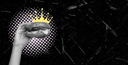 Hand holding a delicious fresh burger on a black background. The concept of delicious and unhealthy food.の写真素材