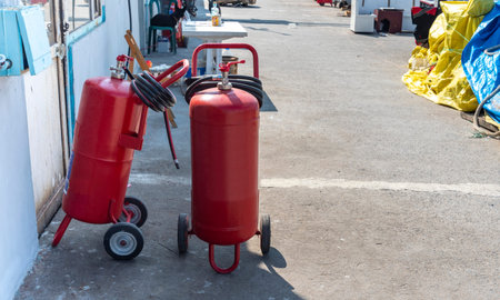 Two bright red fire extinguishers are positioned next to each other on a concrete surface in a...