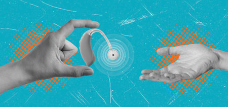 Hands are shown exchanging a small hearing device against a bright blue background. The image highlights advanced technology aiding communication for those with hearing difficulties.の写真素材