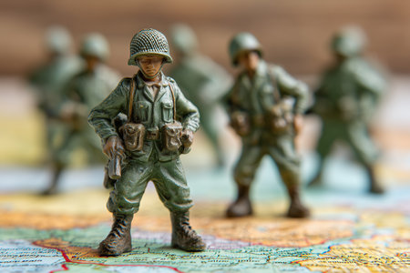 Small soldier figurines are placed on a large map. Children often use these toys for playtime battles. The figures show armed soldiers in action poses, ready for games.の素材