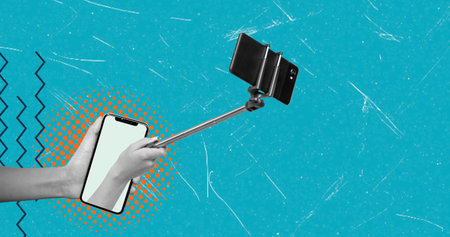 A hand holds a selfie stick that supports a smartphone. The background displays bright colors and geometric shapes. This scene captures a moment of taking a self-portrait.の写真素材