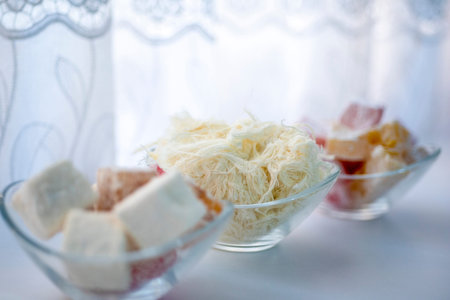 Three bowls hold different kinds of sweets. One bowl contains fluffy strands of candy, while the...