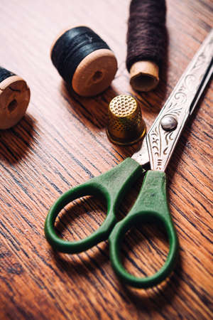 tailor the tool to measure the length,  scissors, spools of colored thread on a wooden backgroundの写真素材