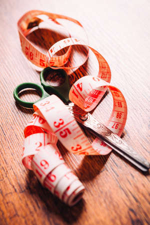 tailor tool for measurement of length and a pair of scissors on the wooden  backgroundの写真素材