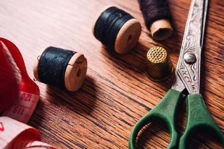 tailor the tool to measure the length,  scissors, spools of colored thread on a wooden backgroundの写真素材