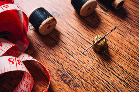 tailor the tool to measure the length,  scissors, spools of colored thread on a wooden background