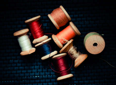 Retro sewing items: tailoring scissors, cutting knife, thimble, wooden thread spools, cushion for including pins, fabrics and sewing accessories.の写真素材