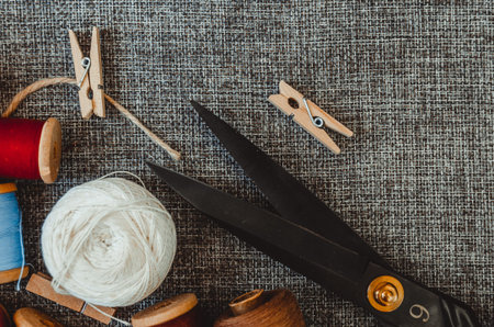 retro sewing tools: old scissors, bobbins of thread on gray fabric. Tailor's desk. manufacture of...
