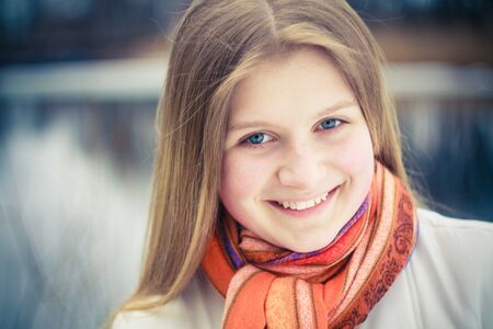 teen girl wearing orange scarf in windy dayの写真素材