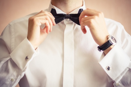 Closeup of business man adjusting neck bow over brown backgroundの写真素材