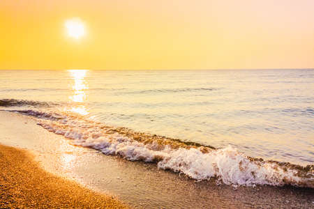 Soft sea ocean waves wash over golden sand background. Sunset, sunise, sunの写真素材
