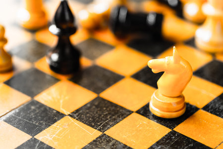 White chess knight and black bishop figures standing on chessboard