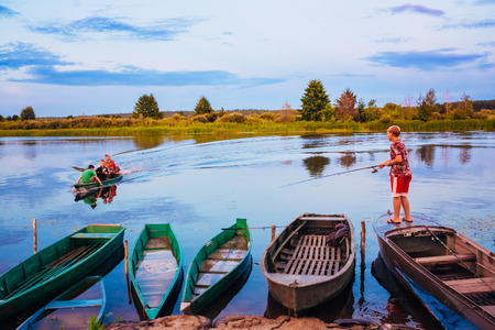 MINSK, BELARUS - JULY 25: Belarusian Boy Fishing From Old Boats At Sunset Of A Summer Day On July 25, 2013 in Minsk, Belarusのeditorial素材