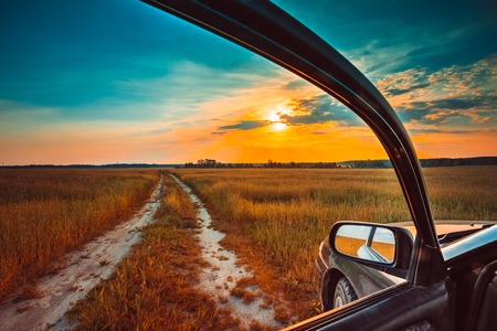 Dirty rural road in autumn fall field, meadow, countryside. View from car window. Freedom and dream concept