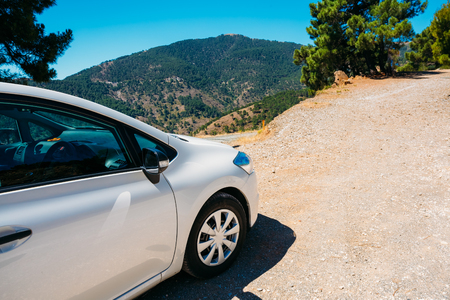 White color small hatchback car on Spainish nature landscape background.の写真素材