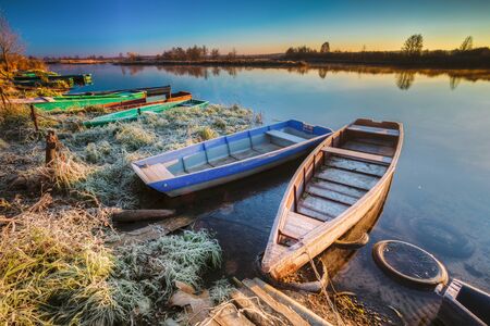 River and old wooden rowing fishing boat at beautiful sunrise in autumn morning.の写真素材