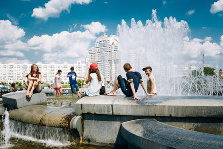 Minsk, Belarus - June 2, 2015: Young People Sit Resting Near Fountain In Summer Heat. Nemiga Ditrict In Minsk, Belarusのeditorial素材
