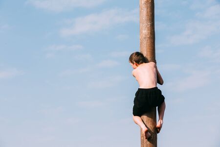 Gomel, Belarus - March 12, 2016: Young man climbs on a wooden post on the traditional holiday dedicated to the approach of spring - Slavic celebration Shrovetide.のeditorial素材