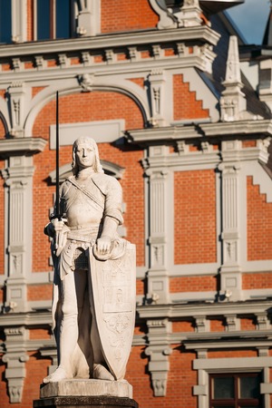 Statue Of Roland At The Town Hall Square On The Background Of The House Of Blackheads In Riga, Latvia. Sunny Summer Day With Blue Sky. Famous Landmark. Old Architecture. Travel Destinationの写真素材
