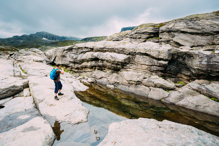Tourist Young Man Photographs Beautiful Landscape Of Norwegian Mountains. Nature Of Norway. Travel And Hiking. Active Lifestyle. Amazing Scenic View. Scandinavia Travel.の写真素材